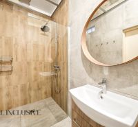 A bathroom in a family house with wooden decor and a round mirror.