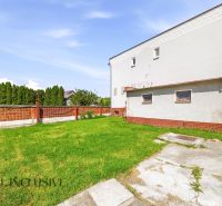 A garden at a family house in Topoľníky with a lawn and a brick fence.