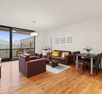 Living room in a 2-room apartment with a wooden decor floor and a spacious terrace.