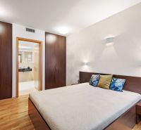 A bedroom in a two-room apartment with a wooden decor floor and built-in wardrobes.