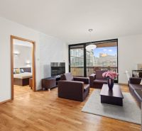 Living room in a two-room apartment with a wooden decor floor and a balcony.