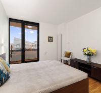Bedroom with wood-patterned flooring, large windows, and a decorative planter.