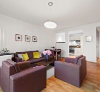 A living room with colorful sofas, wooden decor flooring, and a dining table in a two-room apartment.