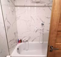 Bathroom in a 2-room apartment with a bathtub, marble tiles, shower head.