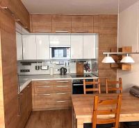 A kitchen in a 2-room apartment with white cabinets and wooden decor.