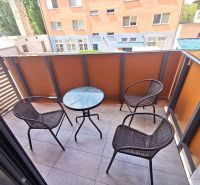 A balcony in a 2-room apartment with three chairs and a table.