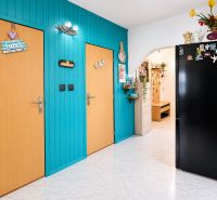 Colorful hallway in a 3-room apartment with wooden doors and a black refrigerator.