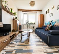 Living room with a sofa and a wooden-decor floor in a three-room apartment.