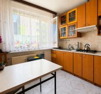 A kitchen in a 3-room apartment with a view, wooden cabinets, flowers on the window.