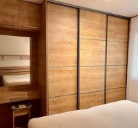 Bedroom in a 2-room apartment with a large wardrobe and a floor with a wooden decor.