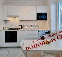A kitchen in a 2-room apartment with white cabinets and marble tiles.