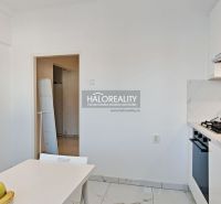 A kitchen in a 2-room apartment with a gas stove and a dining table.