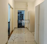 The hallway of a 2-room apartment with white walls and tiles, wardrobes on the sides.
