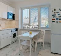 A kitchen in a 2-room apartment with light furniture and a large window.