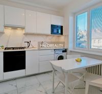 A kitchen in a 2-room apartment with white cabinets and a dining table.