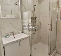 A bathroom in a 2-room apartment with a sink, shower, and marble tiles.