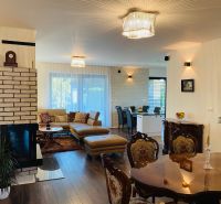 Living room in a family house with wood-patterned flooring and a fireplace, elegant dining room.