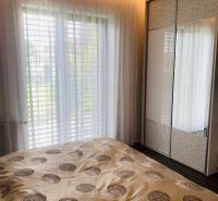 A bedroom in a family house with a large bed, a wardrobe, and curtains on the windows.