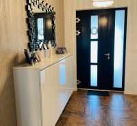Entrance hall in a family house with a wooden decor floor and a mirror on the wall.