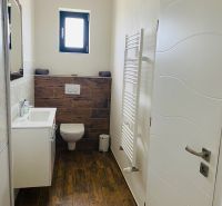 A bathroom in a family house with a wooden decor floor, a white sink, and a window.