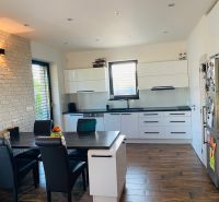 A kitchen in a family house with white cabinets, a table, and a wooden decor floor.