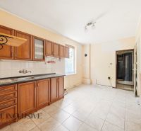 A kitchen with tiles and wooden cabinets in a family house.