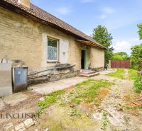 The exterior of an older family house in Lehnice, with an unkempt yard and a clay facade.