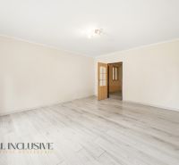 A spacious room with a wooden-patterned floor in a family house.
