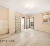 A room in a family house with a wooden decor floor and a door to the kitchen.