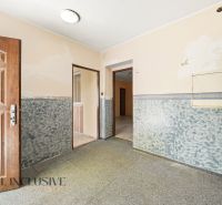 A hallway in a family house with light walls and open doors.