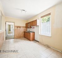 A kitchen in a family house with white tiles and wooden decor cabinets.