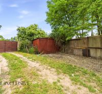 The garden of a family house in Lehnice with a metal gate and greenery.