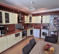 A kitchen with a corner countertop and a wooden decor floor in a 3-room apartment.