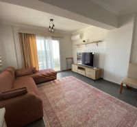 Living room of a three-room apartment with a sofa set and a television on a floor with a wooden decor.