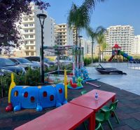 A children's playground by the pool and modern apartment buildings in the city of Iskele.