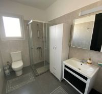 A bathroom in a 3-room apartment with a corner shower and simple furnishings.