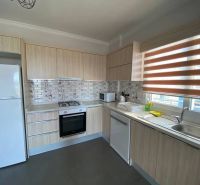 A kitchen in a 3-room apartment with white appliances and tiled backsplash.