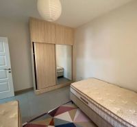 A bedroom in a three-room apartment with two beds, a wardrobe, and a colorful carpet.