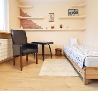 Bedroom in a 3-room apartment with a bed, chair, table, and floor with wooden decor.