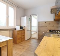 A kitchen in a 3-room apartment with a wooden floor decor and appliances.