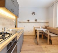 A kitchen in a 3-room apartment with a stove, a wooden table and a bench, a floor with a wooden decor.