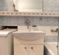 A bathroom with light blue tiles and a combination of a bathtub with a sink in a 3-room apartment.
