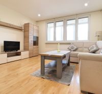 Living room in a 3-room apartment with a wooden decor floor, a sofa, and a TV stand.