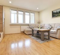 Living room in a 3-room apartment with a wooden decor floor, a light sofa, and a table.