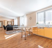 A kitchen in a 3-room apartment with a wooden decor floor, seating, bright lighting.