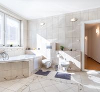 A bathroom in a 3-room apartment with a corner bathtub and light tiles.