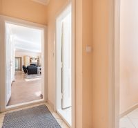 A hallway in a 3-room apartment with a wooden decor floor and furniture.