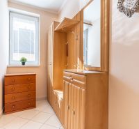 A narrow hallway with wooden furniture and tiles in a 3-room apartment.
