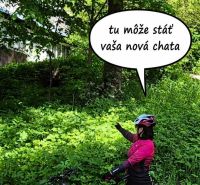 A cyclist in Terchová points to plots - housing surrounded by dense greenery.