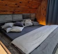A bedroom in a cottage with a comfortable bed and wooden walls.